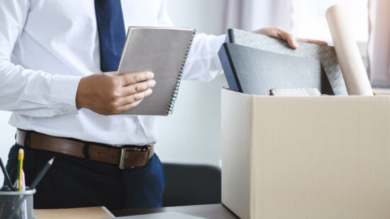 personnel packing personal belongings and files into a brown car